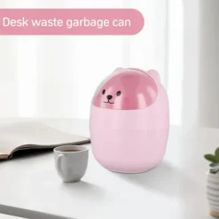 Dette er en lille, lyserød skrivebordsaffaldsspand til børn med låg. Det er også en mini, aftagelig penholder lavet af sød plastik med et flip-top design. | Fyndiq